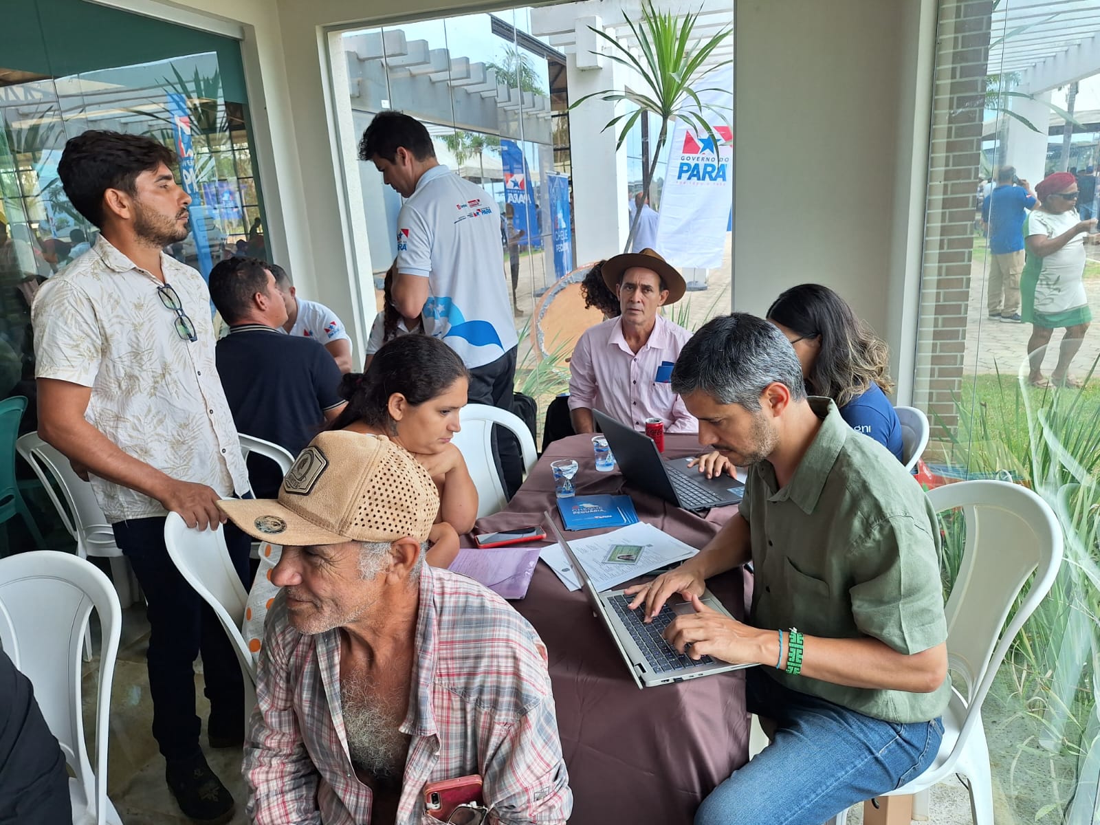 Sete pessoas sentadas e duas de pé em mutirão para cadastramento
