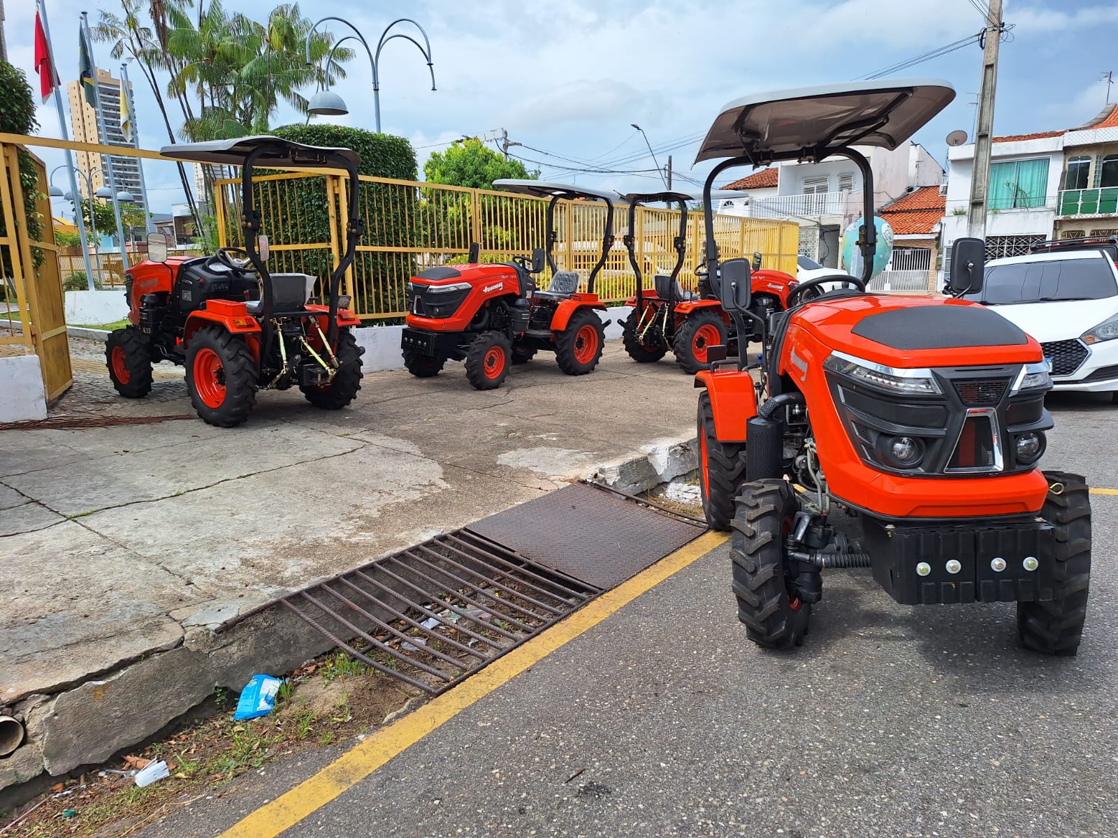 Imagem mostra 4 pequenos tratores na calçada e rua 