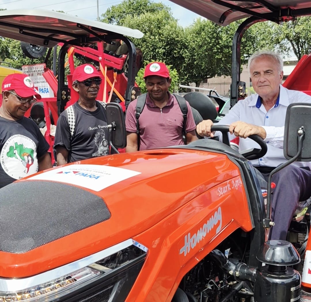 imagem mostra quatro pessoas, uma delas em um pequeno trator