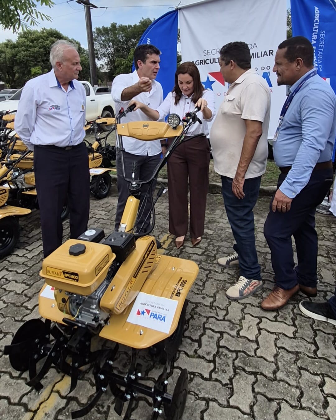 imagem mostra quatro homens e uma mulher ao centro manuseando uma máquina agrícola