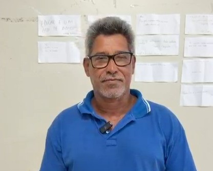 imagem mostra homem pardo, cabelos grisalhos, camisa azul
