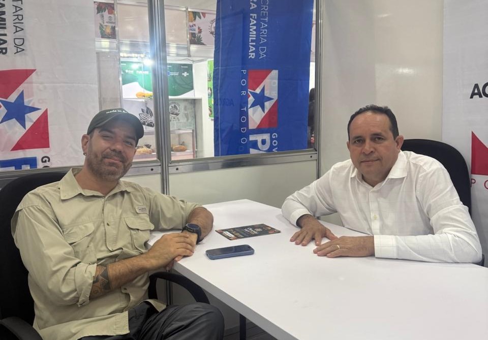 Imagem mostra dois homens sentados em uma sala olhando para a camera da foto